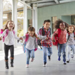 Skolebarn løper mens de holder hverandre i hendene