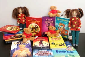 Barnebøker og Vilja-dukken utover et bord