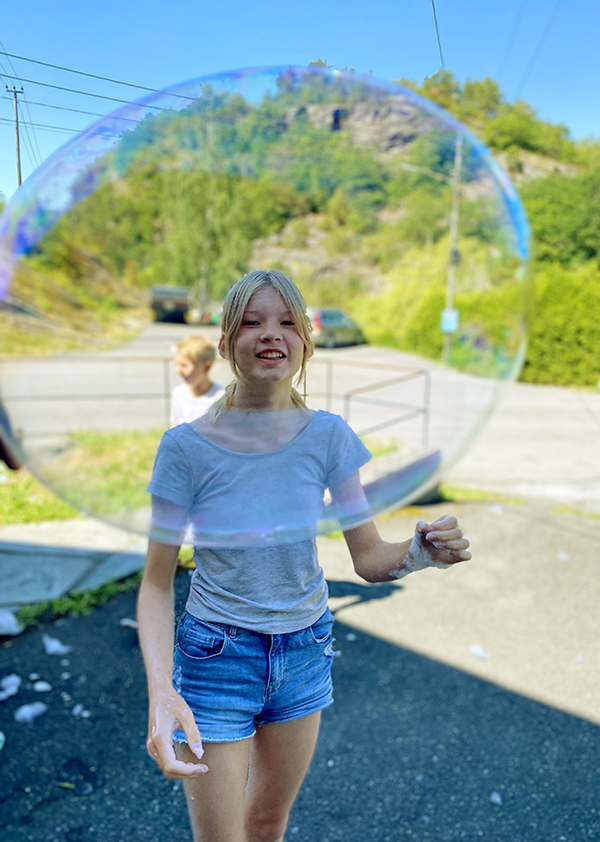 Ung jente utendørs med kjempestor såpeboble