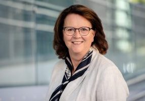 Portrett av kvinne med brunt halvlangt hår og briller