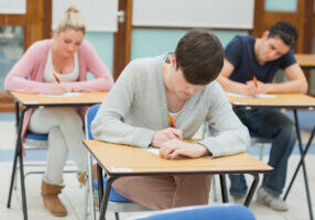 Elever skriver ved pultene sine