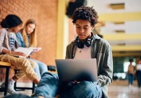 Gutt med laptop og headset sitter i skolegang